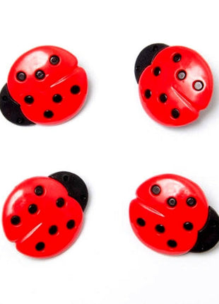 Four red plastic buttons with black ladybird spots and a plastic shank visible on a white background.