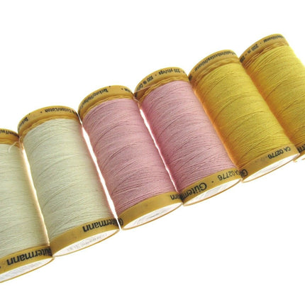Set of six spools of thread in various colors on a white background