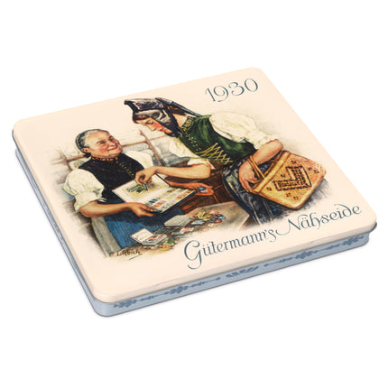 A square vintage-style tin or box lid featuring an illustrated scene of two people in traditional clothing, with the text '1930' and 'Gittermanns Nähseide' printed on the lid. The object is photographed on a clean white background.