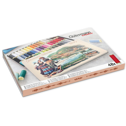 Gütermann 48 x Polyester sew all thread set in a decorative tin showing a variety of colorful threads and a scenic German landscape illustration on the front.