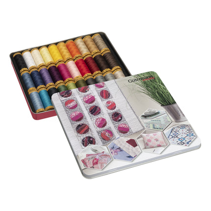 A Gutermann thread tin set shown open, with rows of colorful sewing thread spools in a red-lined metal box and the matching lid placed in front, featuring printed fabric and sewing-themed illustrations.