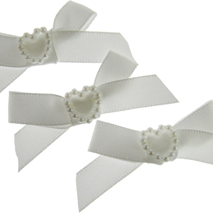 Three white hair bows with pearl centers on a white background