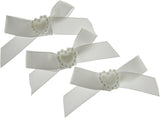 Three white hair bows with pearl centers on a white background