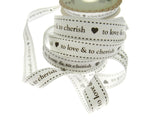 Spool of ribbon with text 'to love & to cherish' on a white background