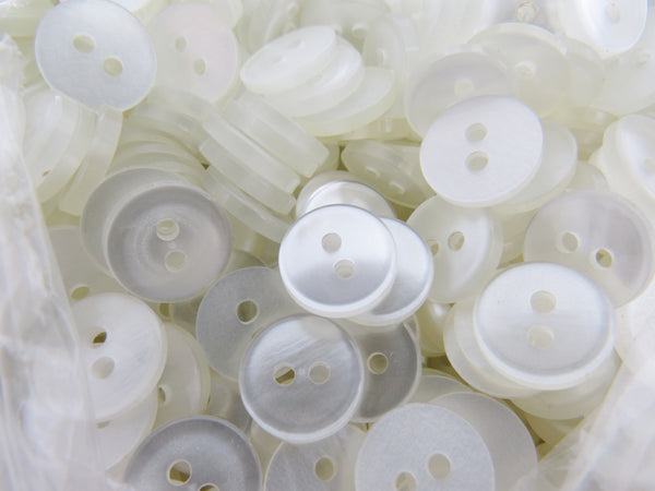 Close-up of a pile of white shirt buttons with two holes.