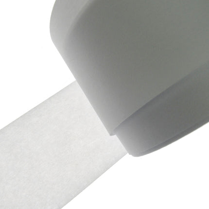 A close-up of a white roll of double sided fusible iron on stabilizer, with a strip unrolled diagonally against a solid white background.