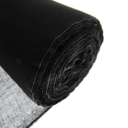A close-up of a rolled 100% cotton fusible iron on black interfacing fabric, showing its fine woven texture and sheer quality, with a small section of the unrolled black fabric visible in the bottom left corner against a white background.