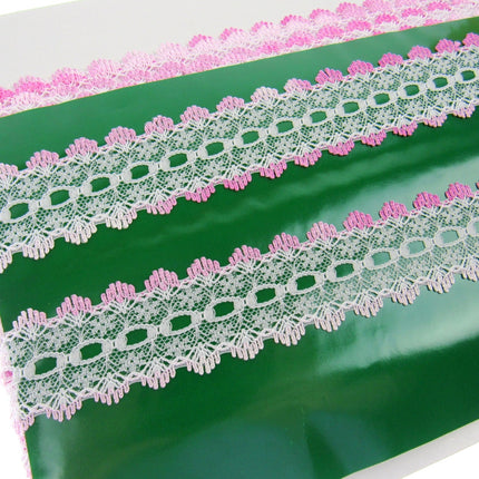 White floral lace trim with pink edges, shown in multiple lengths on a green background.