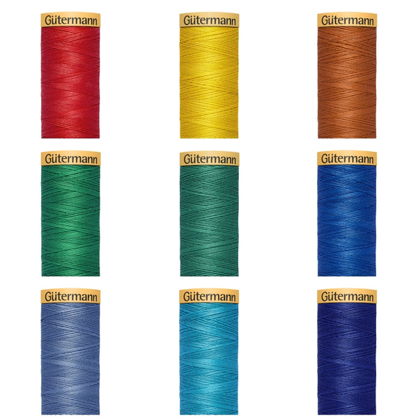 Six spools of Gütermann thread in red, yellow, brown, green, and blue on a white background.