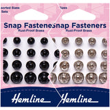 Hemline snap fasteners packaging with black and rust-proof brass options on a pink background.