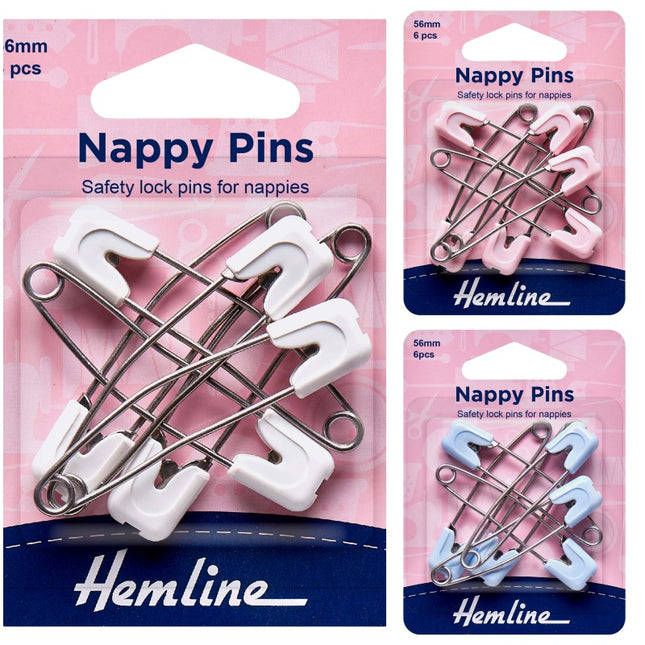 Three retail packages of Hemline nappy pins shown on a pink background. The main package shows six white safety lock pins, with two smaller packages on the right showing pink and light blue versions respectively.