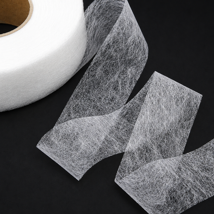 A roll of white fibrous mesh tape or filter paper partially unrolled on a black background, showing the textured, web-like material.