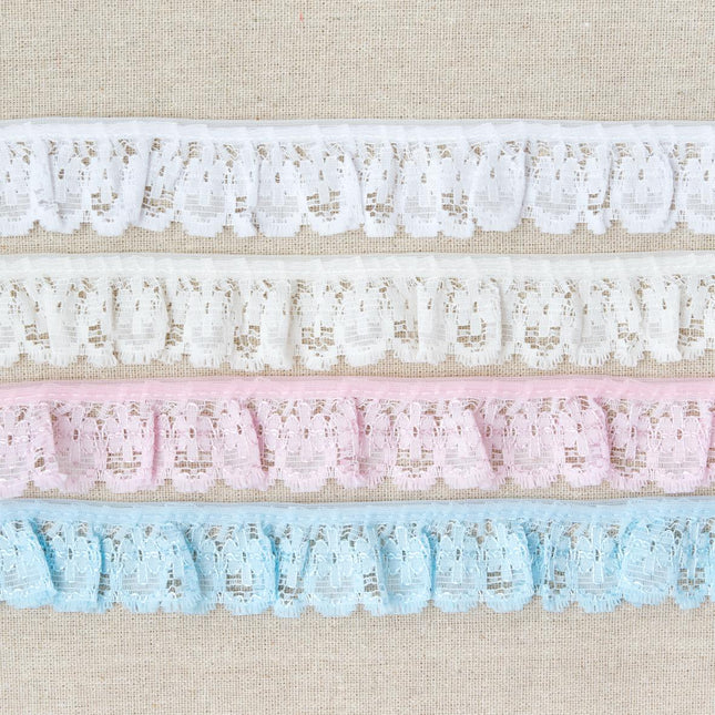 Four horizontal strips of decorative lace trim in white, cream, light pink, and light blue, laid flat on a beige textured fabric background.