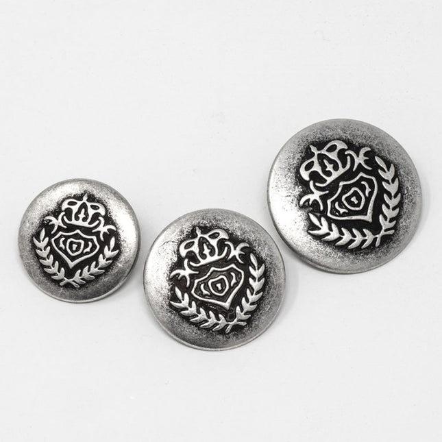 Three round silver-tone decorative buttons with an embossed rose and laurel wreath design, arranged on a plain white background.