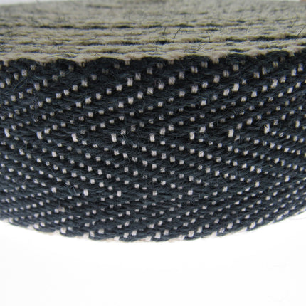 Close-up of a roll of black and white woven Herringbone upholstery webbing on a white background