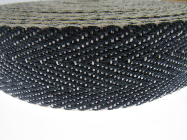 Close-up of a roll of black and white woven Herringbone upholstery webbing on a white background