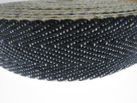 Close-up of a roll of black and white woven Herringbone upholstery webbing on a white background