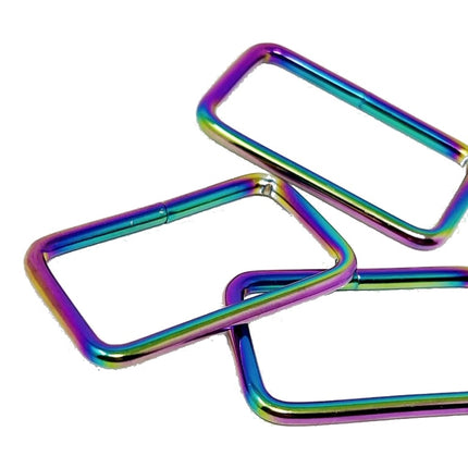 Three square metal rings with rounded corners, featuring an iridescent rainbow finish, arranged on a plain white background.