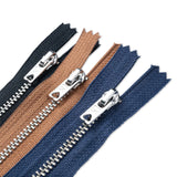 Three zippers in blue, brown, and black with metal pullers on a white background