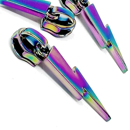 A pair of metallic lightning bolt zip sliders with an iridescent rainbow finish, shown on a plain white background.