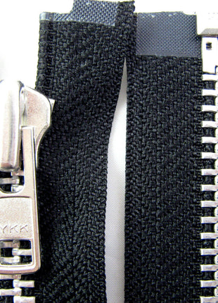 Close-up of a heavy-duty metal open-end zip by YKK, showing the teeth and slider against a black background. 