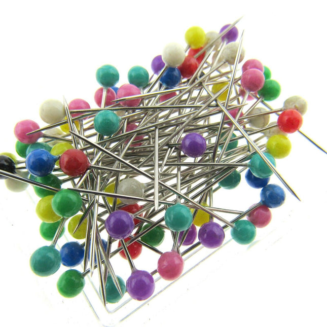 A box of colourful  headed pins with plastic heads on a white background