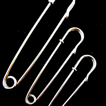 A set of three nickel plated steel kilt pins in varying sizes placed against a black background.