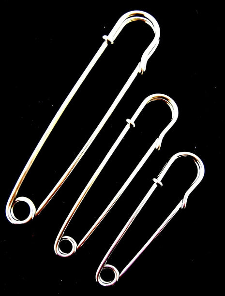A set of three nickel plated steel kilt pins in varying sizes placed against a black background.