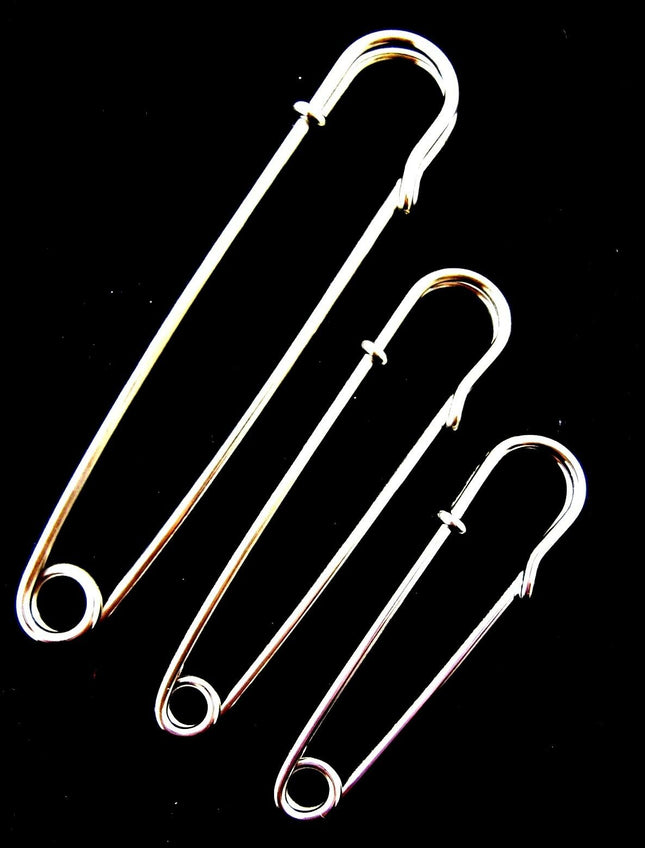 A set of three nickel plated steel kilt pins in varying sizes placed against a black background.
