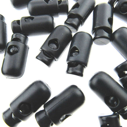 A collection of dark navy barrel-shaped spring loaded cord locks scattered on a surface.