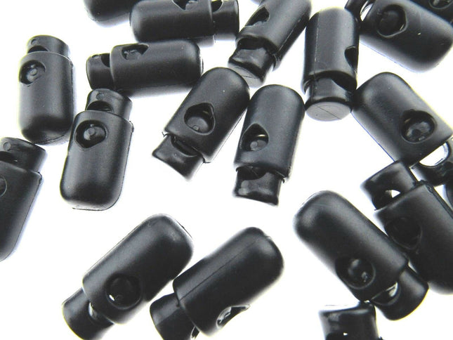 A collection of dark navy barrel-shaped spring loaded cord locks scattered on a surface.