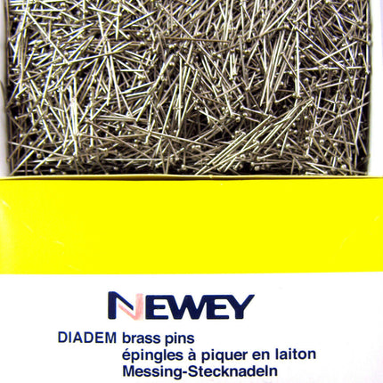 A box of Newey DIADEM brass pins, with the brand name visible on the packaging. The pins are nickel-plated and appear to be straight and uniform in size.