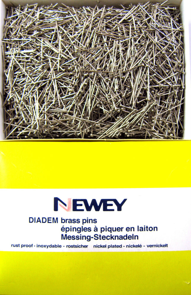 A box of Newey DIADEM brass pins, with the brand name visible on the packaging. The pins are nickel-plated and appear to be straight and uniform in size.