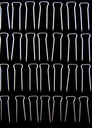 An array of double pointed pins used for upholstery, displayed in rows on a dark background.