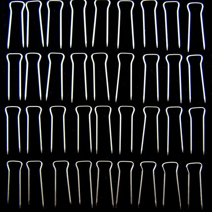 An array of double pointed pins used for upholstery, displayed in rows on a dark background.
