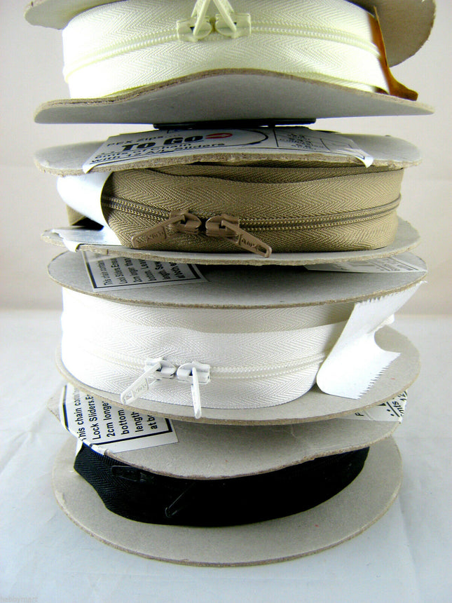 A stack of continuous zip chains in various colors including black, white, cream, and fawn, each with a slider.