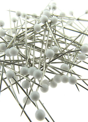 White glass head pins on a white background