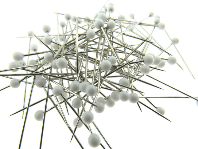White glass head pins on a white background