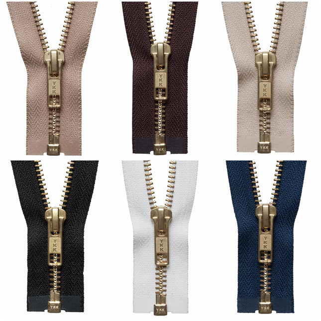Close up view of a genuine YKK number five brass metal open end zipper showing the medium weight golden teeth and slider mechanism.
