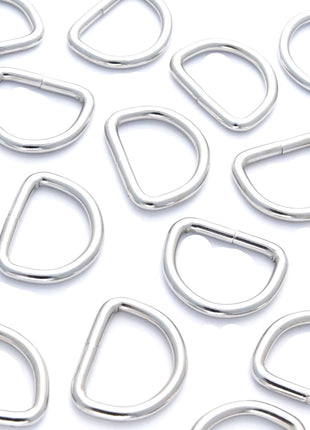 A collection of silver nickel-plated solid welded D rings in various sizes arranged on a white background.