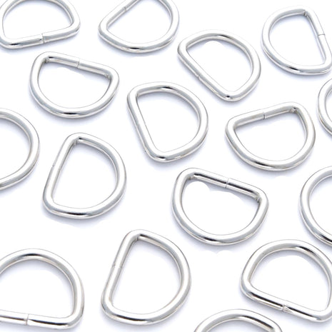 A collection of silver nickel-plated solid welded D rings in various sizes arranged on a white background.