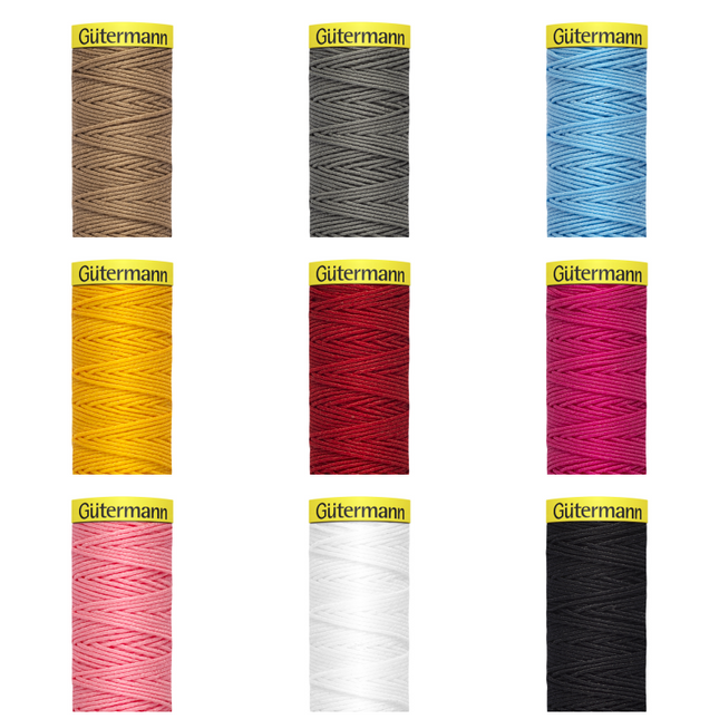 Multiple reels of Gutermann elastic thread in various colors including brown, gray, black, red, pink, white, and yellow.