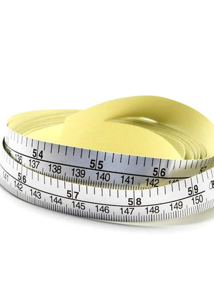 A silver-colored self-adhesive tape measure with printed measurements, partially unrolled and showing the measurement markings.