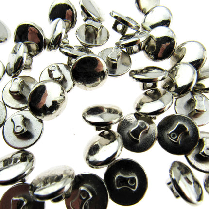 A collection of silver colored plastic mini buttons scattered on a surface.