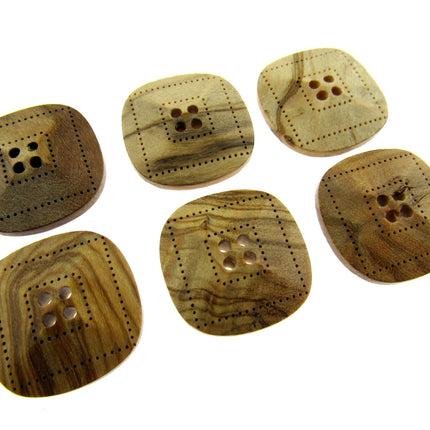 Six square-shaped, beige-colored wooden buttons with four holes each, made from olive wood, displayed on a white background