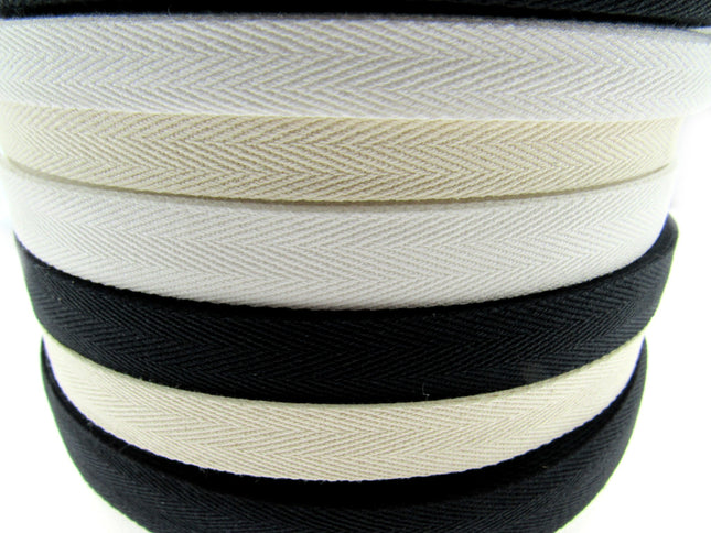 Rolls of cotton twill apron webbing tape in black, white, and beige colours