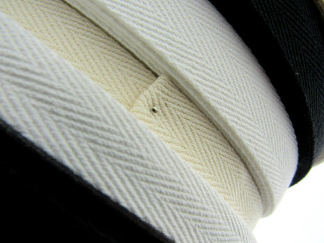 Rolls of cotton twill apron webbing tape in black, white, and beige colours