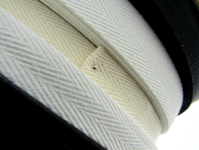 Rolls of cotton twill apron webbing tape in black, white, and beige colours