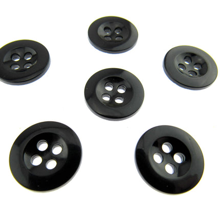 Six four hole black trouser buttons on a white background