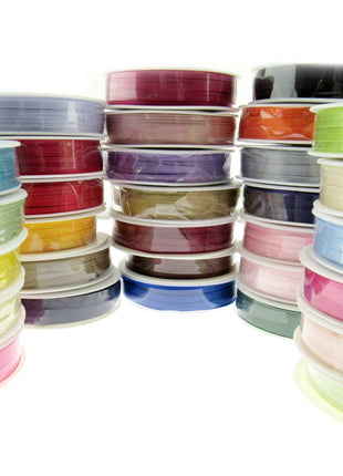 A collection of double faced satin ribbons in various colors, each ribbon is 3mm wide and 50 meters long, displayed in a stacked arrangement.